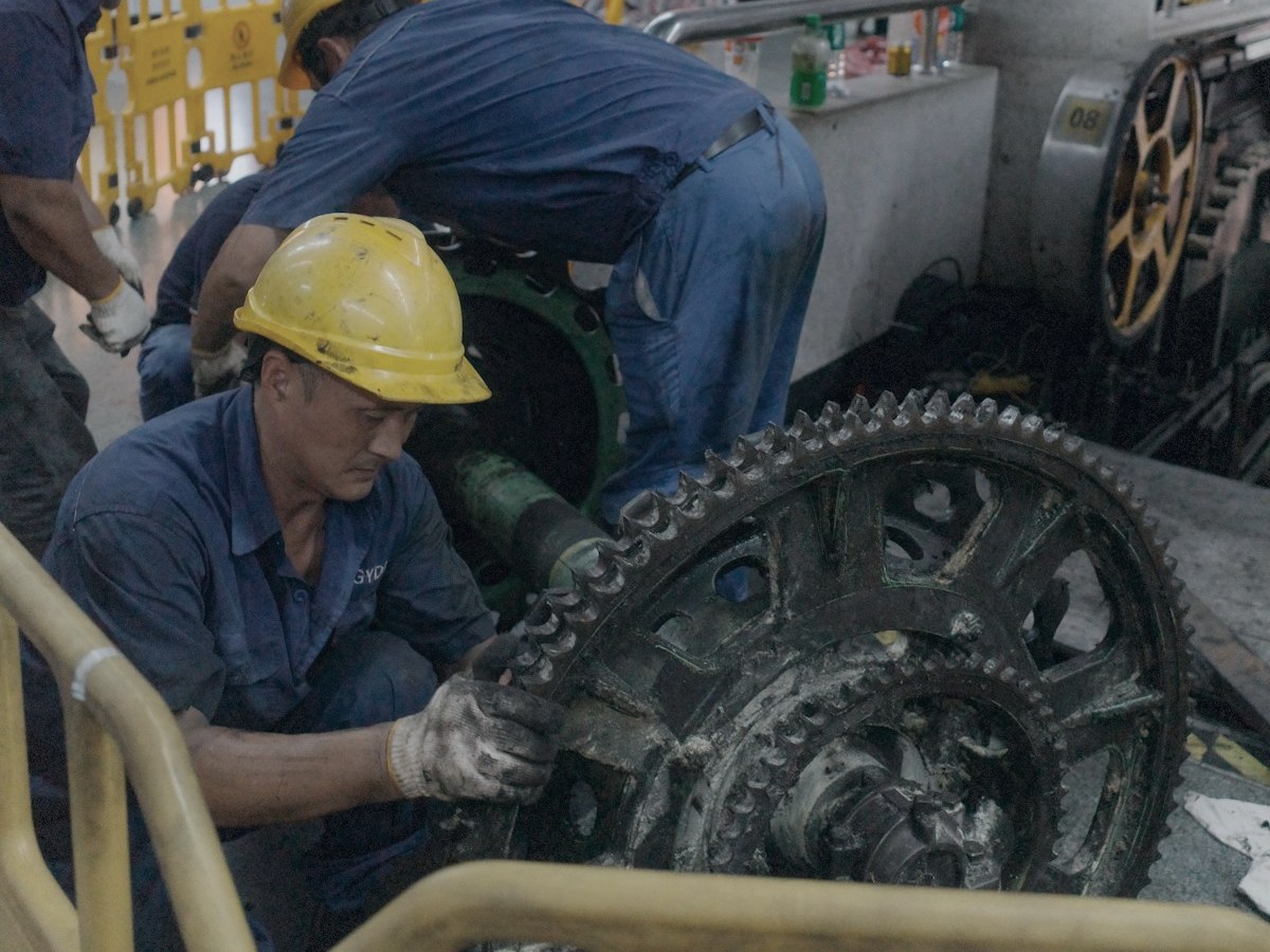 Crew in hard hats and coveralls repairing large industrial gearing during a turnaround